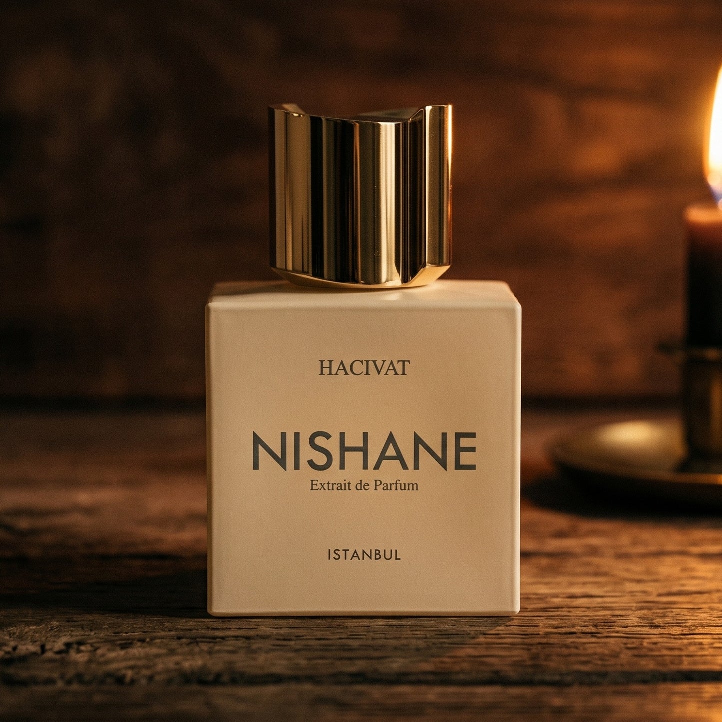 Nishane Hacivat Extrait De Parfum on rosewood surface with a squat brass candle flickering nearby
