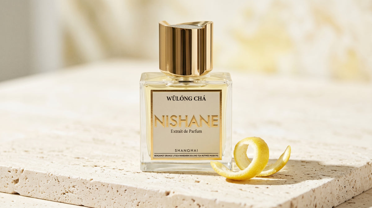 Nishane Wulong Cha EDP on pale travertine with a lemon peel curled beside the bottle