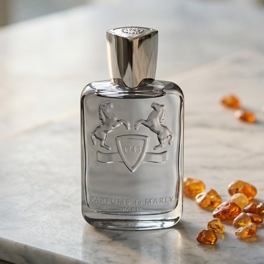 Parfums de Marly Castley EDP on pale grey marble with amber resin beads scattered to one side