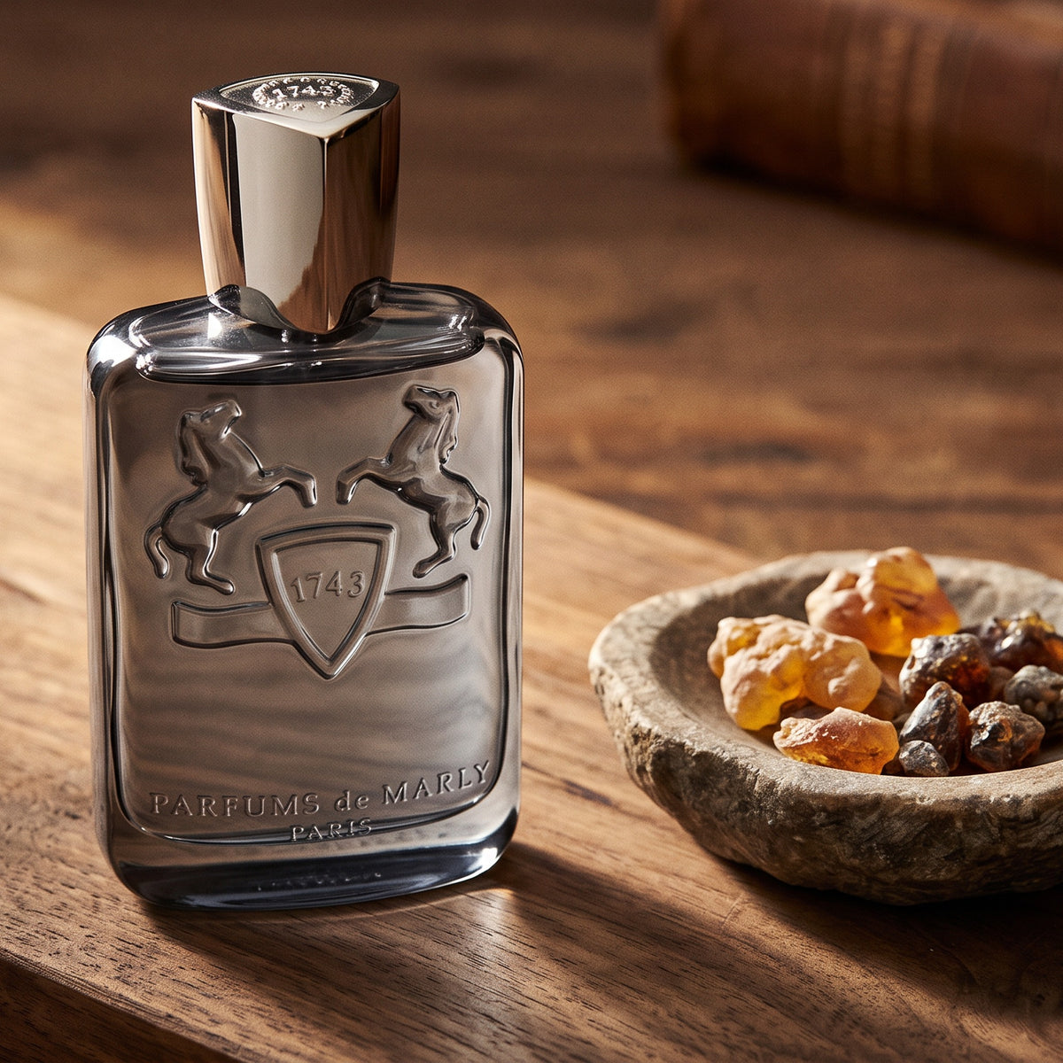 Parfums de Marly Castley EDP on walnut board with a few pieces of labdanum and benzoin in a small stone dish