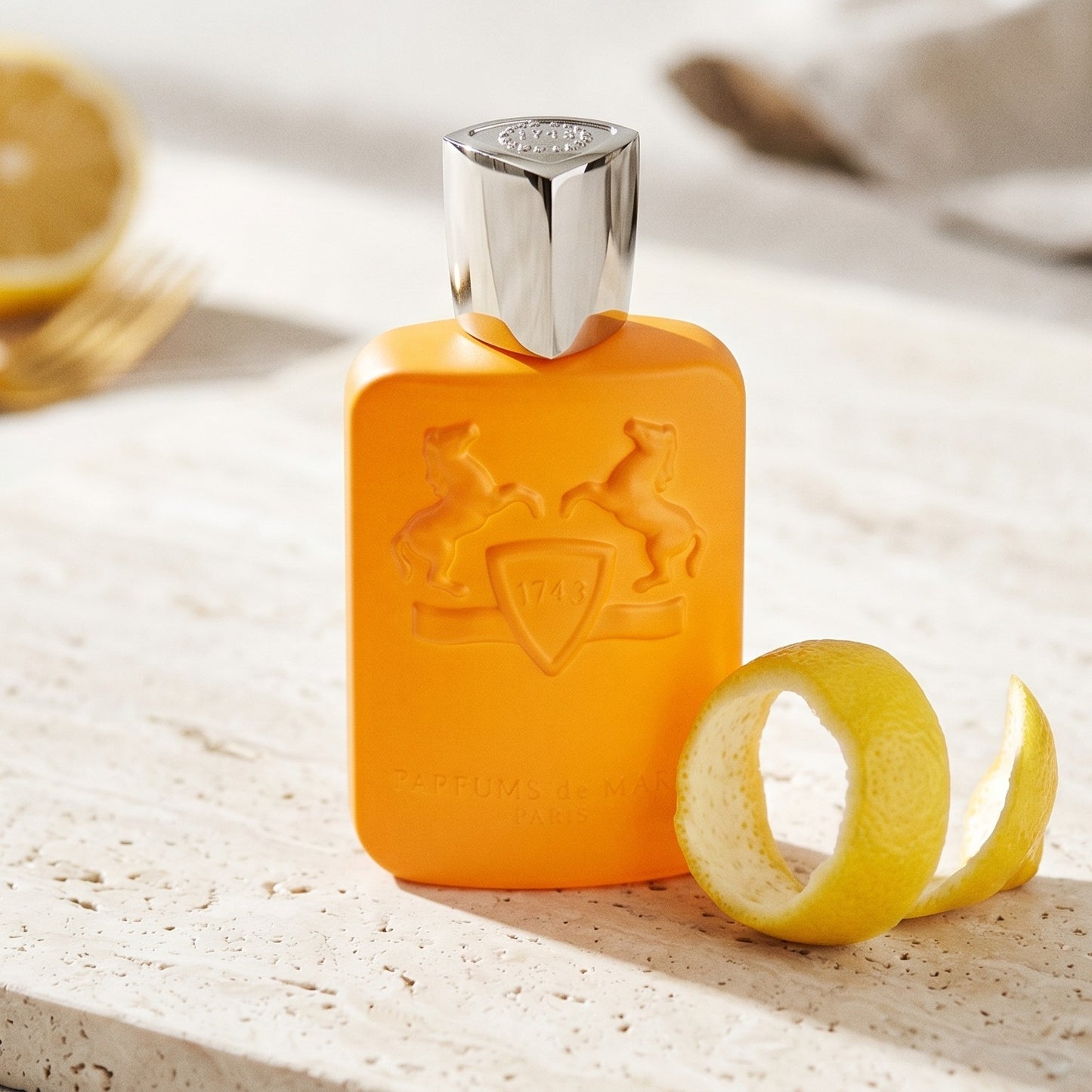 Parfums de Marly Perseus on ivory travertine with lime peel drizzled across the surface