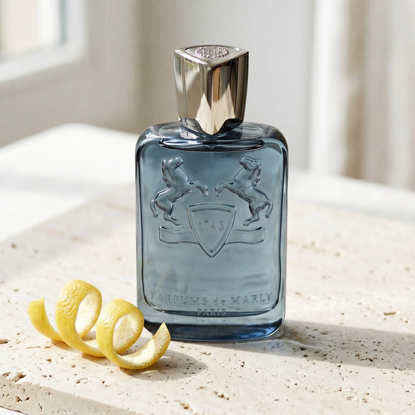 Parfums de Marly Sedley EDP on pale travertine with a lemon peel curled beside the bottle
