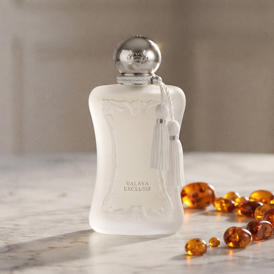 Parfums de Marly Valaya Exclusif EDP on pale grey marble with amber resin beads scattered to one side