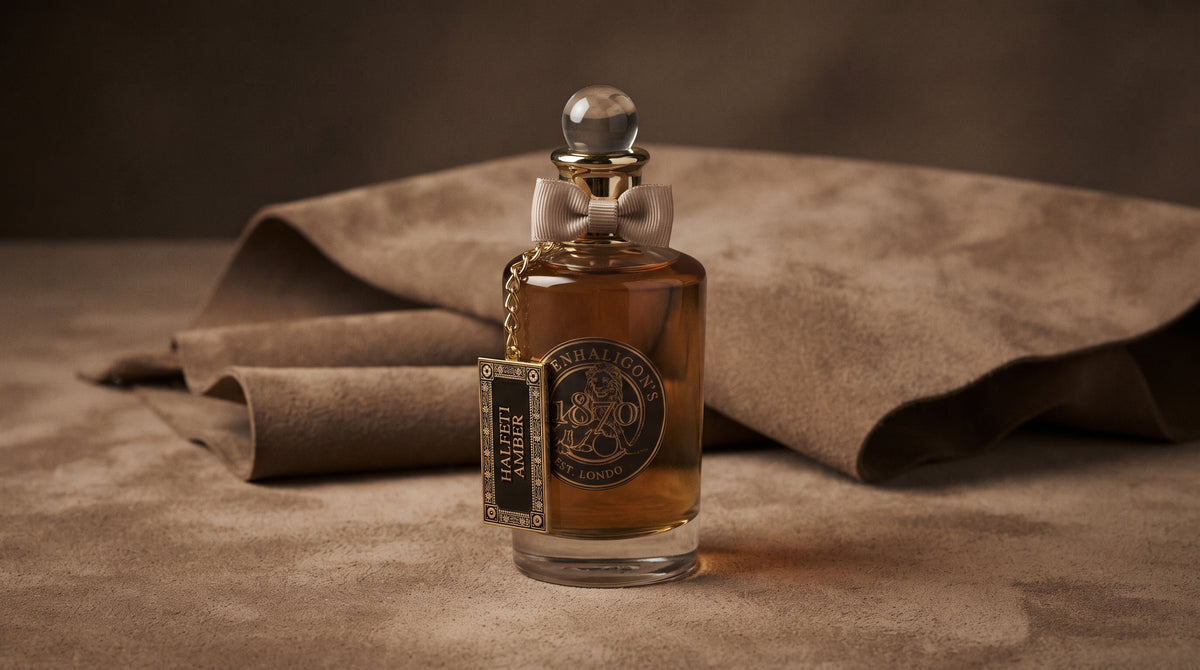 Penhaligon's Halfeti Amber EDP - Dubai Exclusive on warm taupe suede with a folded suede swatch resting just behind the bottle