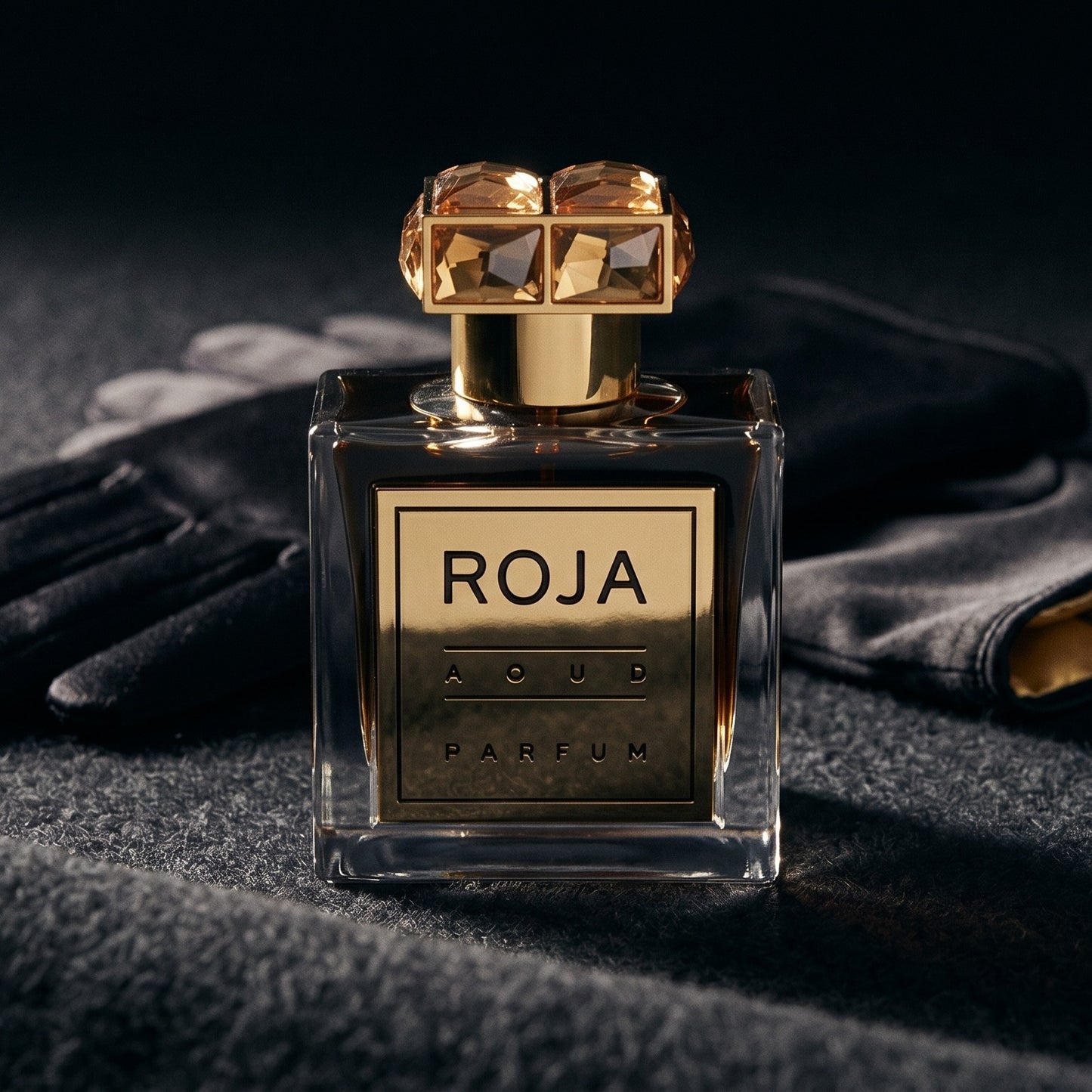 Roja Aoud Parfum Parfum on smoke-grey wool with a folded pair of driving gloves to the side