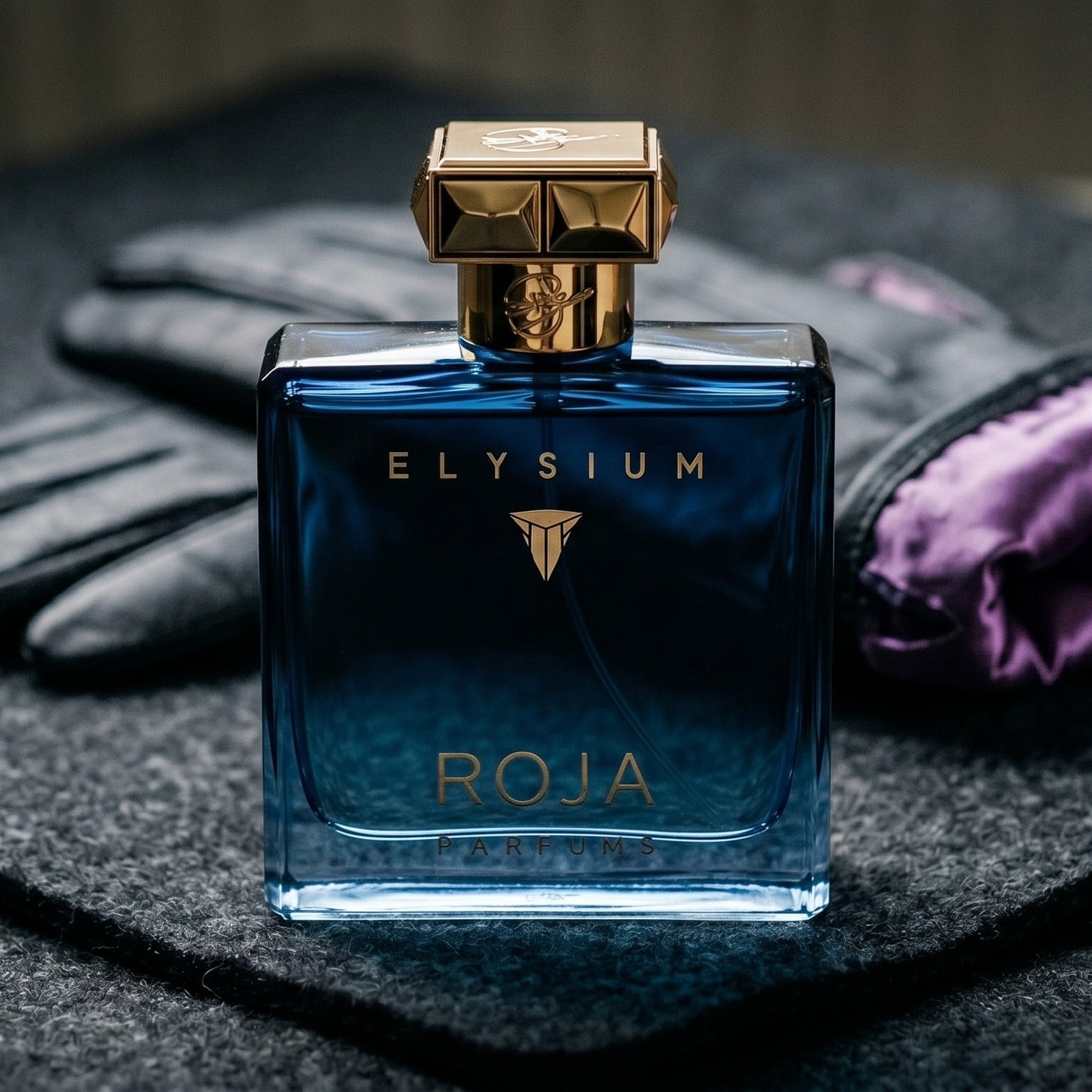 Roja Elysium Parfum Cologne on black suede surface with a folded pocket square beside the base
