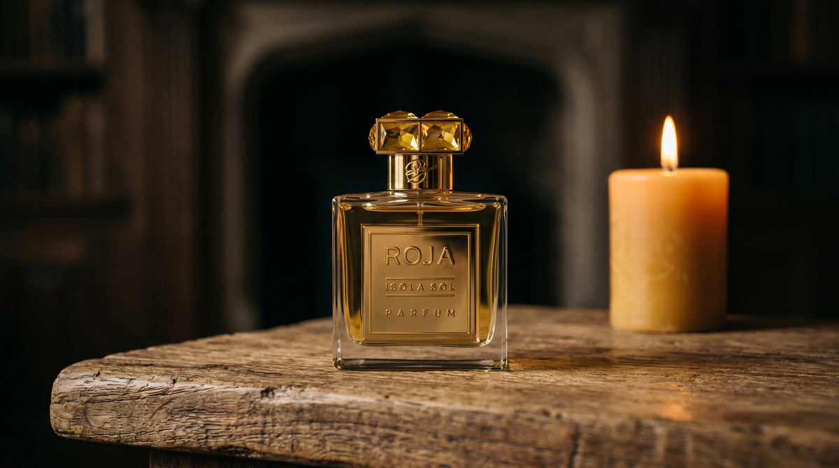 Roja Isola Sol Parfum on aged teak with a candle burning gently to frame-right