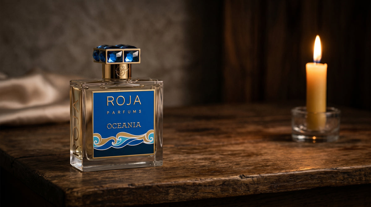 Roja Oceania Parfum on aged teak with a candle burning gently to frame-right