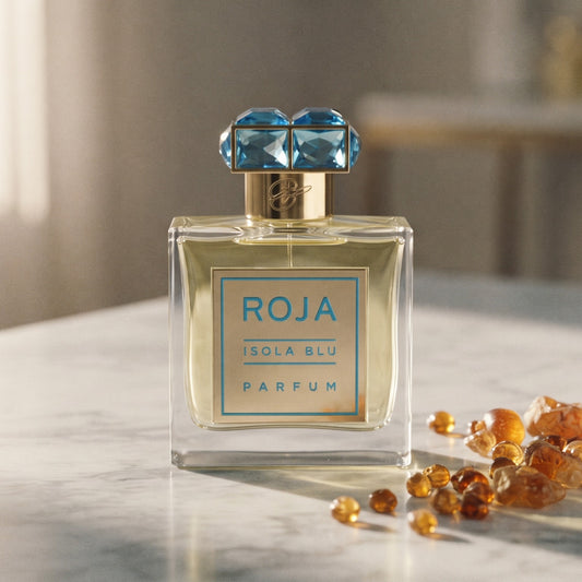 Roja Parfums Isola Blu Parfum on pale grey marble with amber resin beads scattered to one side