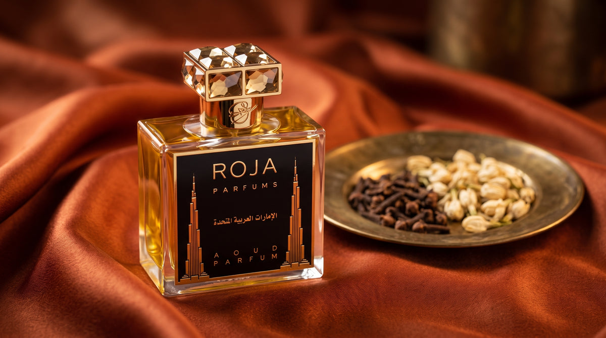 Roja United Arab Emirates Parfum on burnt-orange silk with clove buds and dried jasmine in a small brass saucer