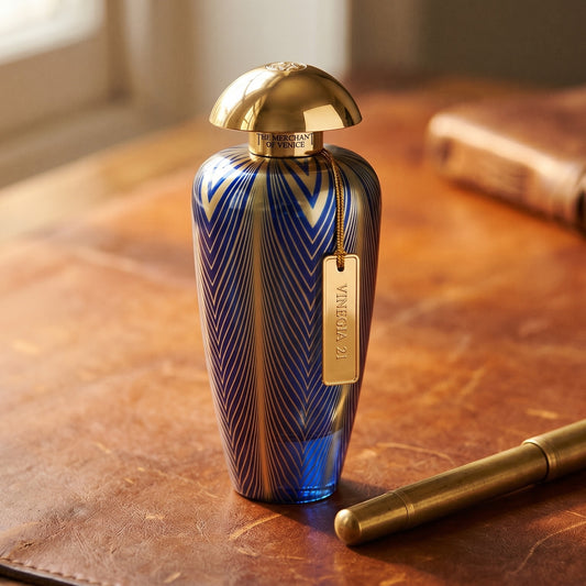 The Merchant of Venice Vinegia 21 EDP on aged cognac-leather surface with a brass fountain pen resting beside it