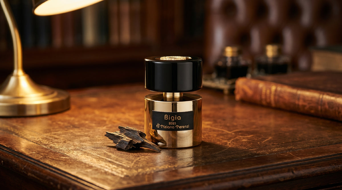 Tiziana Terenzi Bigia EDP on aged leather-topped desk with a single agarwood chip beside the bottle
