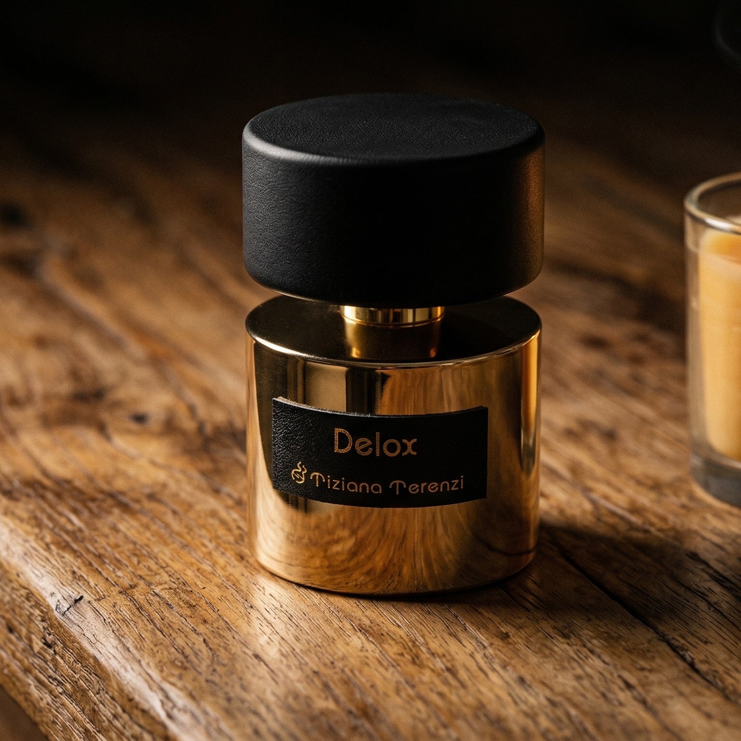 Tiziana Terenzi Delox EDP on walnut side table with a pair of lit votives beside the bottle