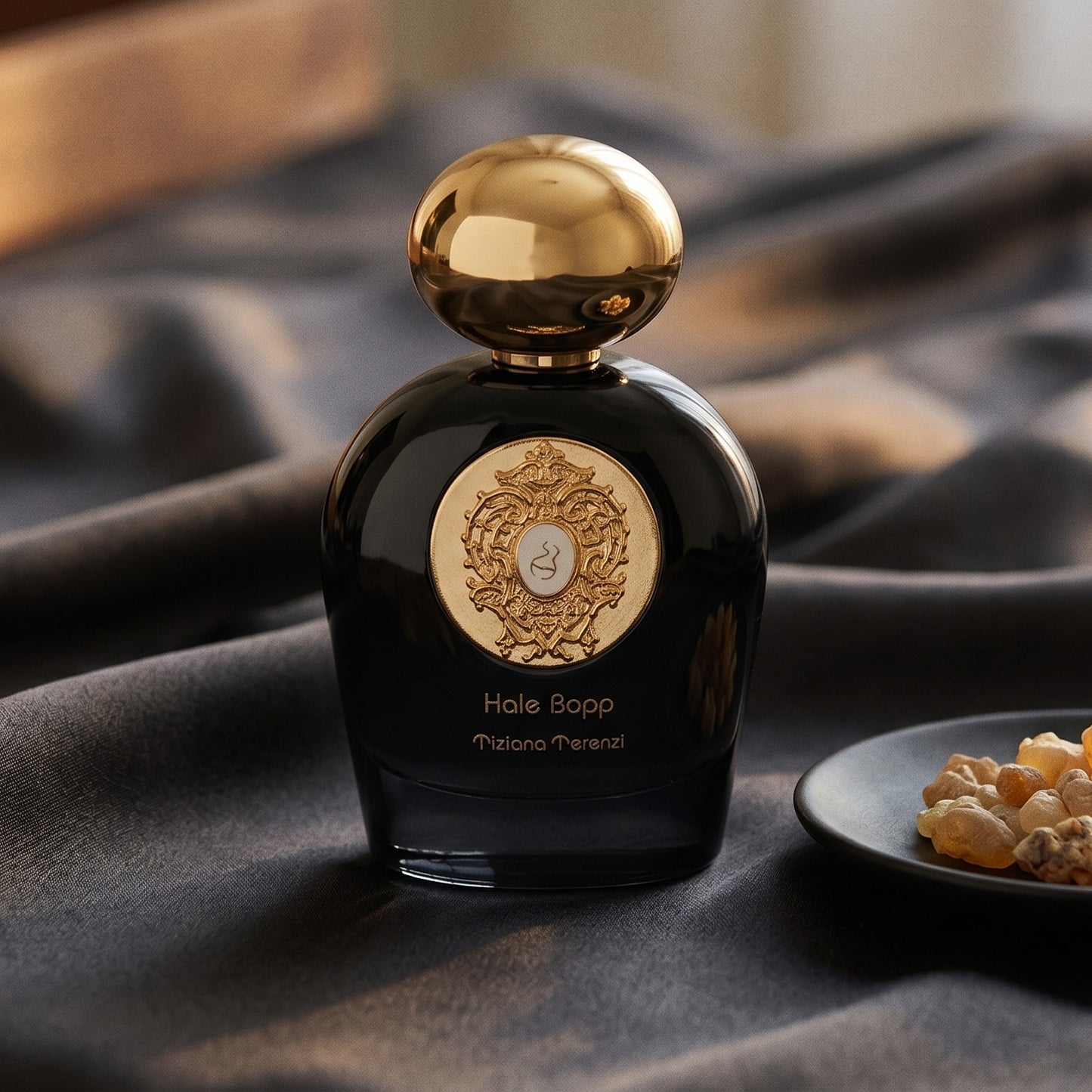 Tiziana Terenzi Hale Bopp Ext on charcoal raw silk with amber resin pieces near the bottle base