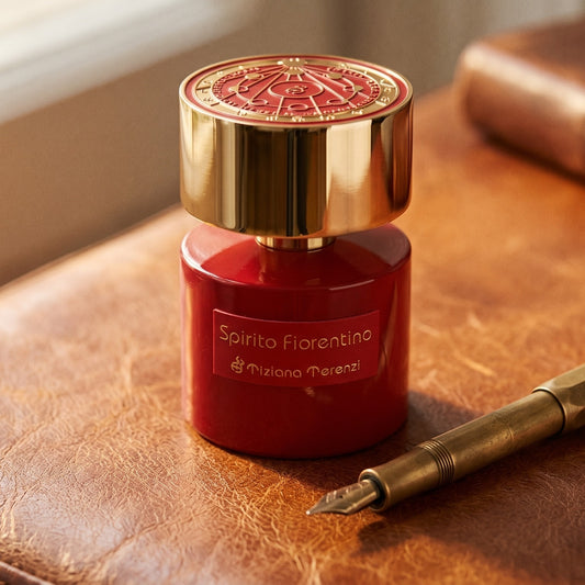 Tiziana Terenzi Spirito Fiorentino EDP on aged cognac-leather surface with a brass fountain pen resting beside it