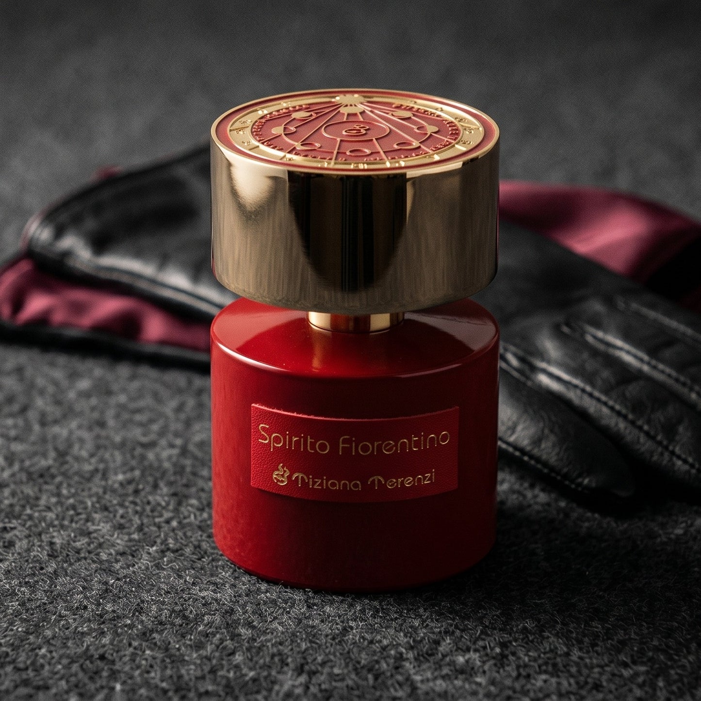 Tiziana Terenzi Spirito Fiorentino EDP on dark grey baize with a braided leather bracelet coiled loosely