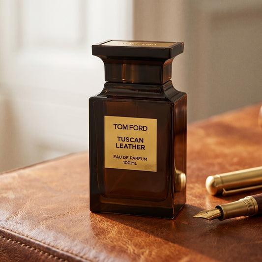 Tom Ford Tuscan Leather on aged cognac-leather surface with a brass fountain pen resting beside the bottle