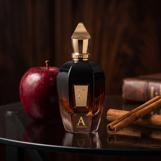 Xerjoff Oud Stars Alexandria II EDP on smoked-glass tabletop with a red apple and two cinnamon sticks