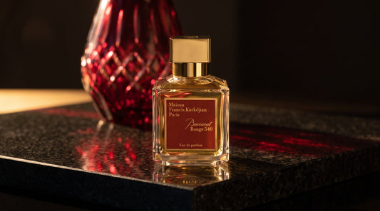 Maison Francis Kurkdjian Baccarat Rouge 540 eau de parfum on dark stone with a red cut crystal vase behind