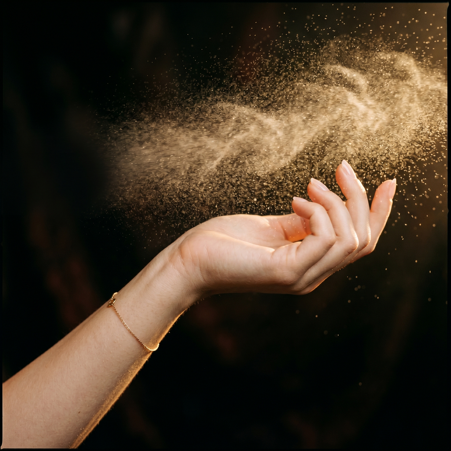 Feminine wrist held upward with fine fragrance mist backlit by warm golden light, demonstrating oud application