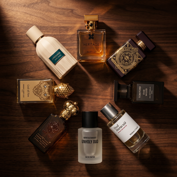 Top-down flatlay of eight oud fragrances on walnut surface