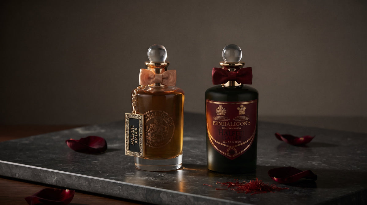 Penhaligon's Halfeti Amber and Halfeti Leather bottles on dark honed stone with dark crimson rose petals and saffron threads