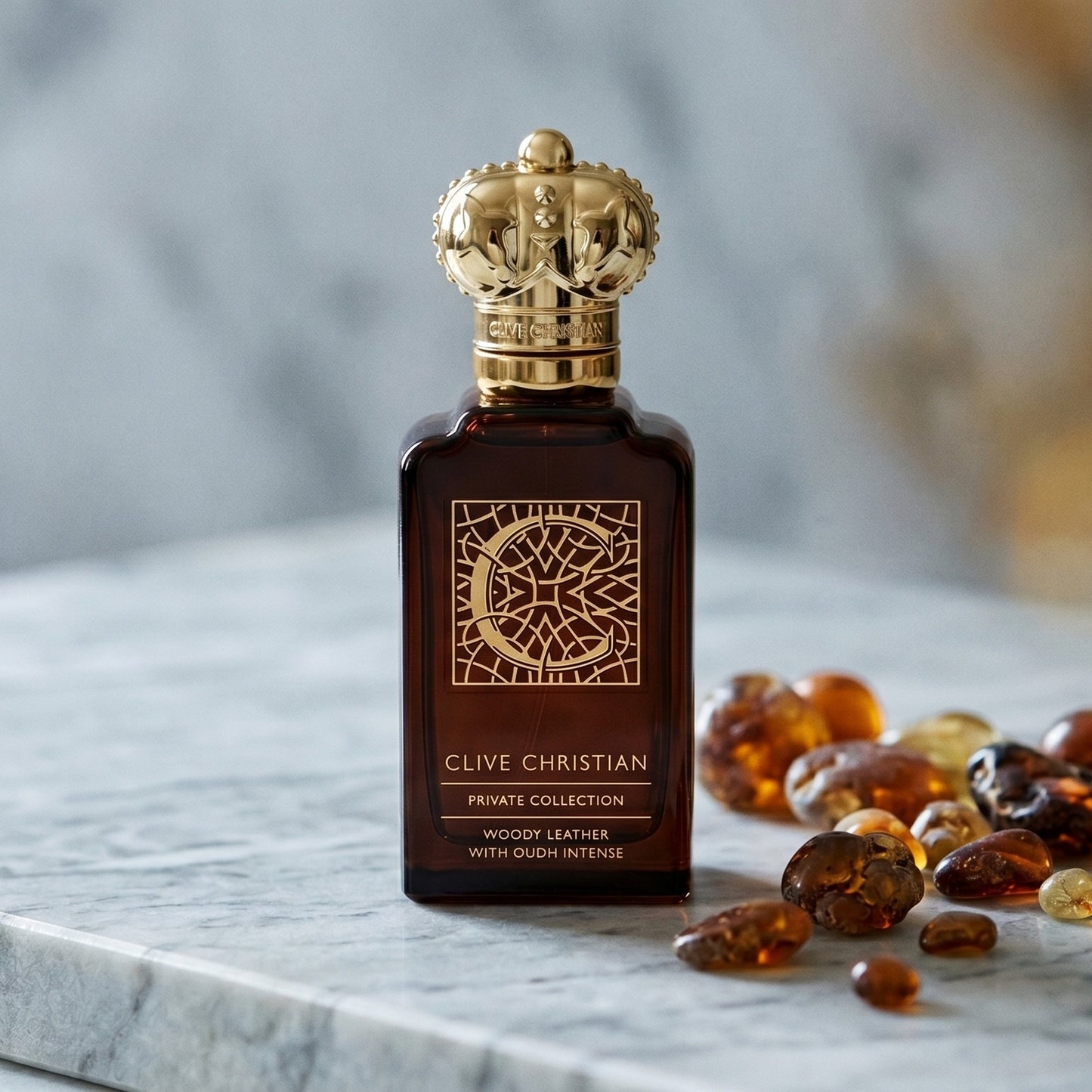 Clive Christian Private Collection (Woody/Leather/Oud/Amber) on pale grey marble with amber resin beads scattered to one side