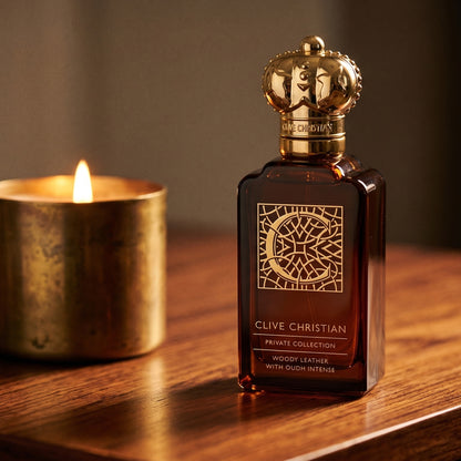Clive Christian Private Collection (Woody/Leather/Oud/Amber) on rosewood surface with a squat brass candle flickering nearby