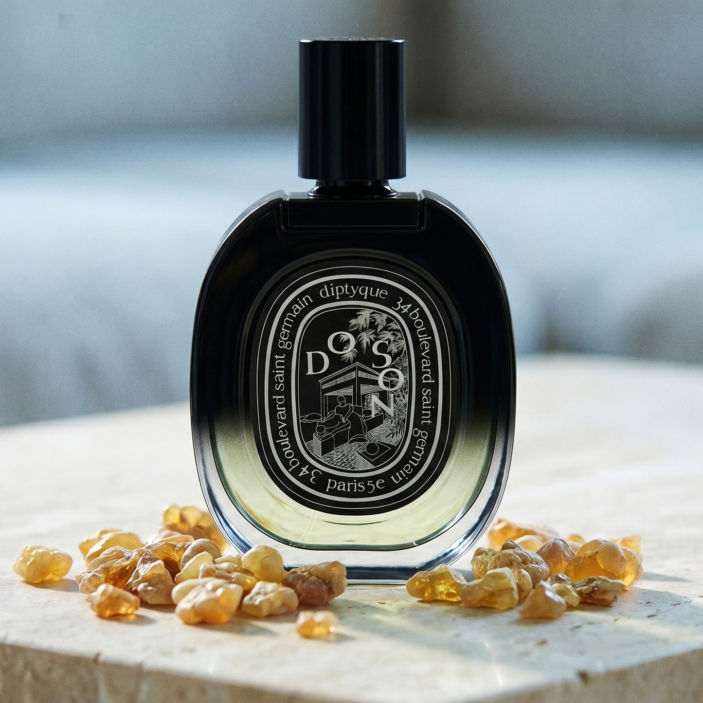 Diptyque Doson EDP on polished limestone with benzoin resin pebbles arranged loosely