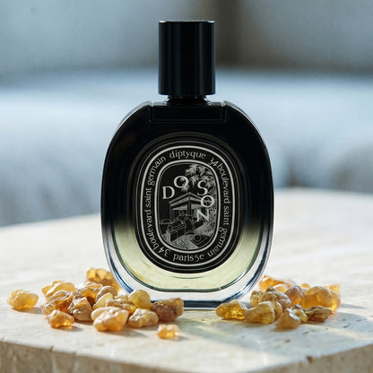 Diptyque Doson EDP on polished limestone with benzoin resin pebbles arranged loosely