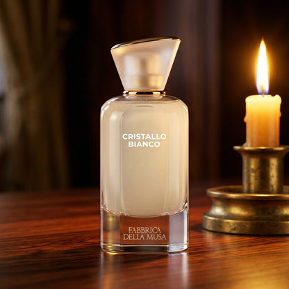 Fabbrica Della Musa Cristallo Bianco EDP on rosewood surface with a squat brass candle flickering nearby