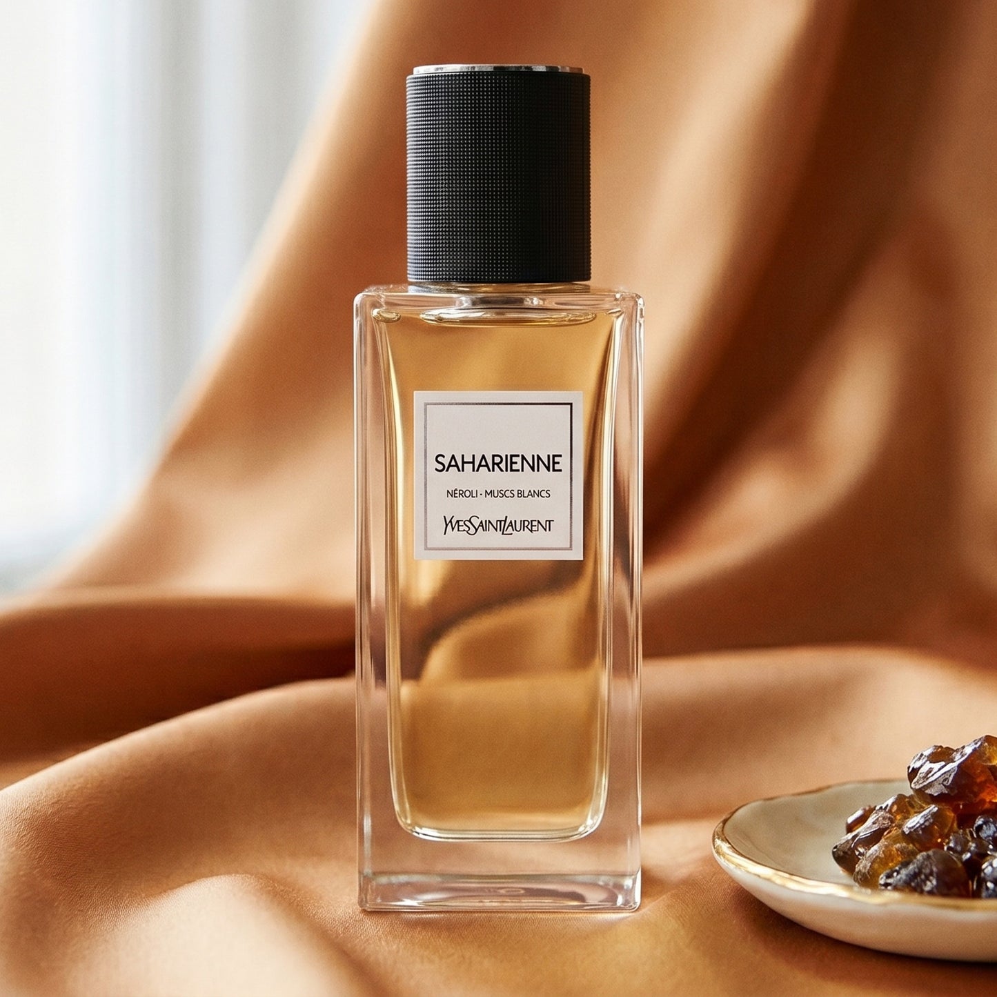 Yves Saint Laurent Saharienne on amber-toned satin with a gold-rim ceramic dish of labdanum