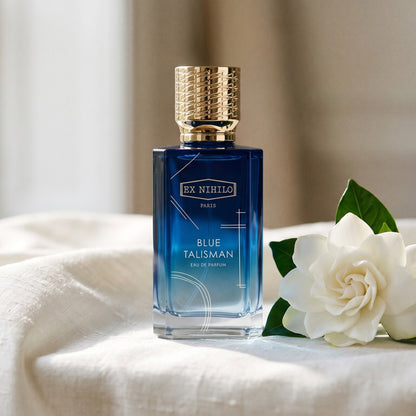 Ex Nihilo Blue Talisman EDP on white raw silk with a gardenia bloom placed beside the bottle