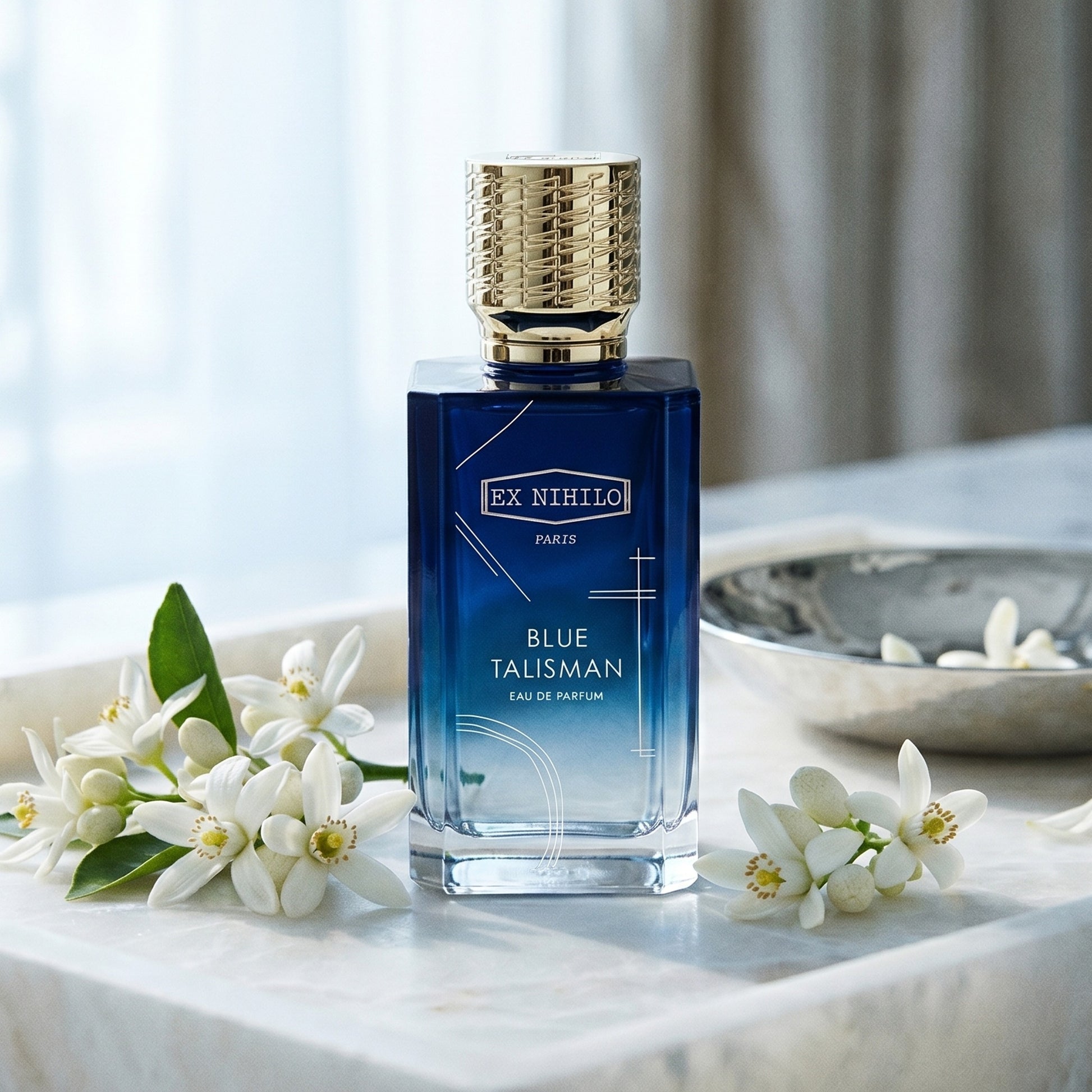 Ex Nihilo Blue Talisman EDP on alabaster tray with neroli blossoms around a silver bowl