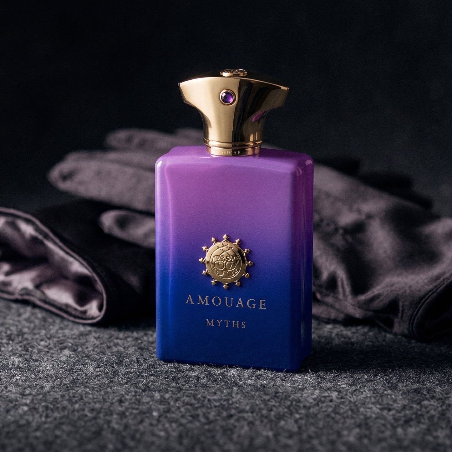 Amouage Myths Man on charcoal felt with a silk-lined glove just behind the bottle