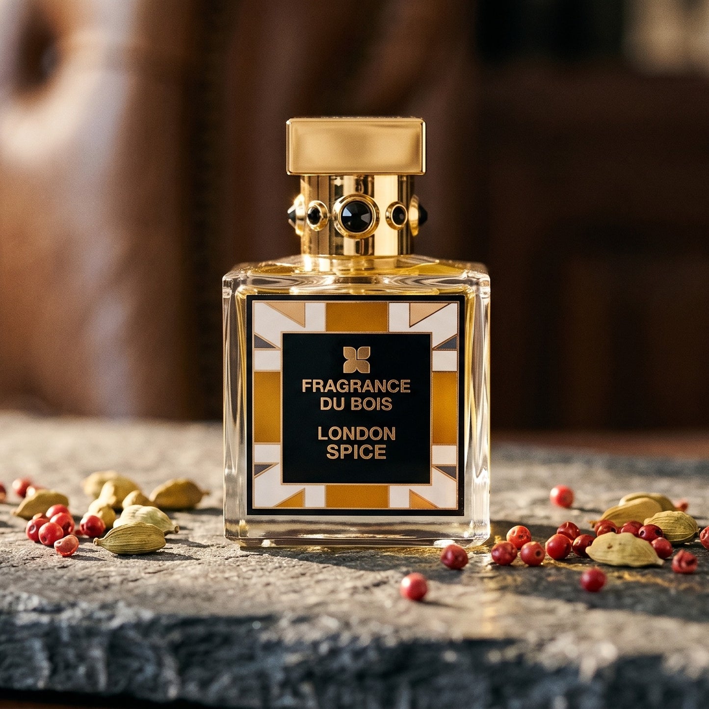 Fragrance Du Bois London Spice on dark grey stone slab with cardamom pods and pink peppercorns scattered