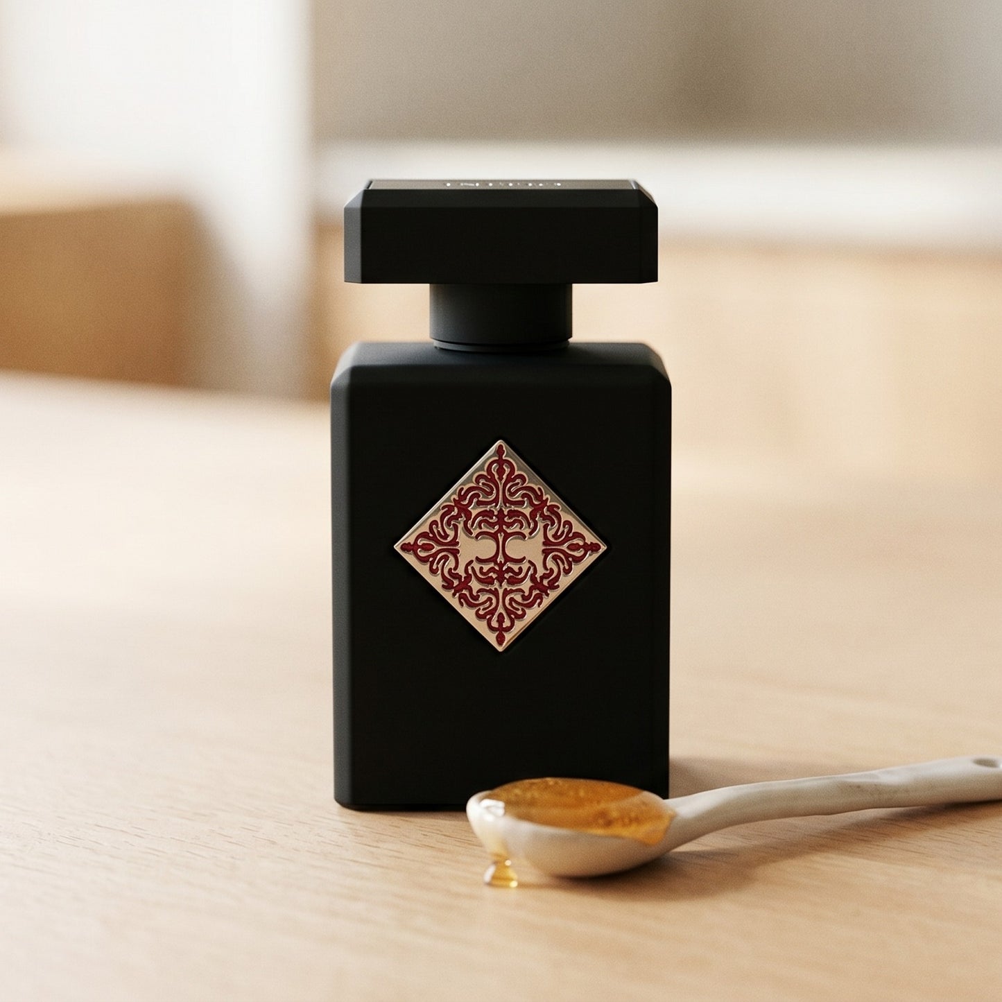 Initio Addictive Vibration EDP on pale beech wood with a small porcelain spoon with honey