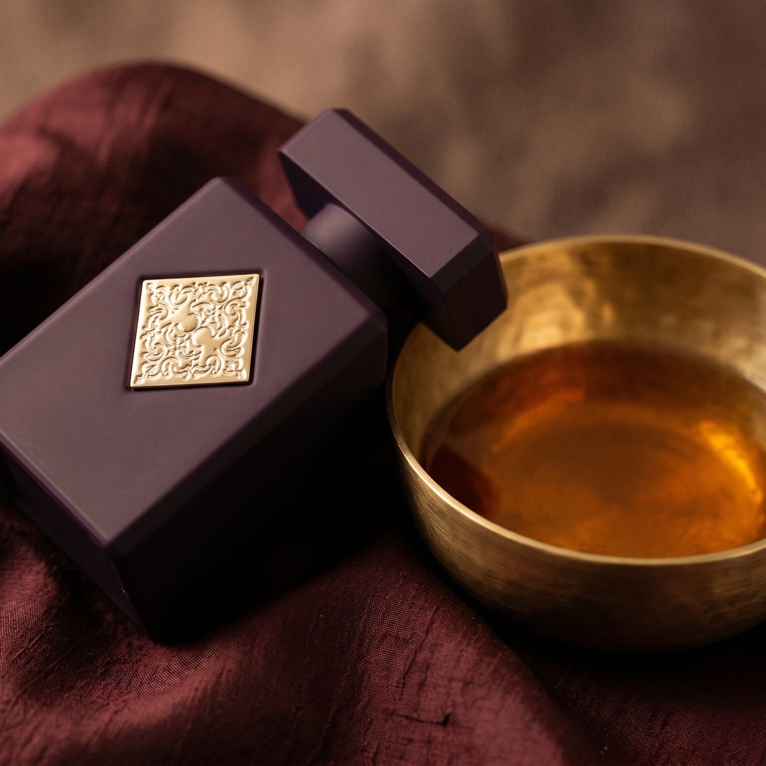 Initio Atomic Rose EDP on raw silk of oxblood color with a brass bowl with ambergris tincture