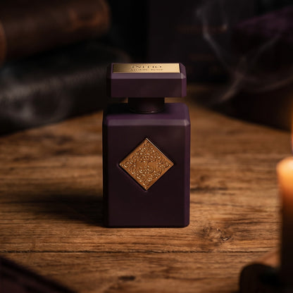 Initio Atomic Rose EDP on aged teak with a candle burning gently to frame-right