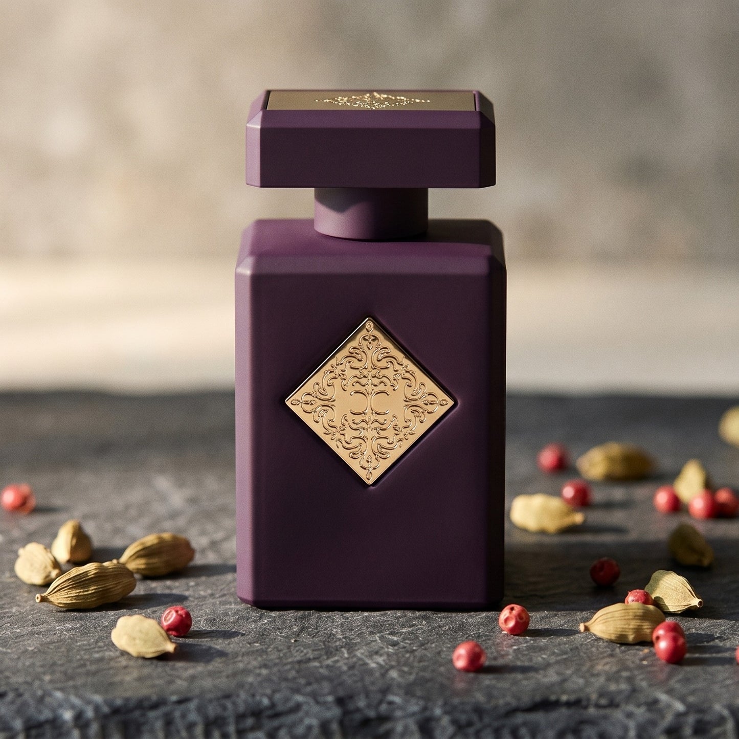 Initio Narcotic Delight EDP on dark grey stone slab with cardamom pods and pink peppercorns scattered