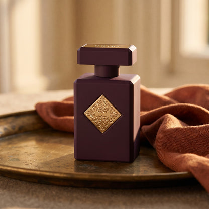 Initio Narcotic Delight EDP on aged brass tray with a folded pashmina in rust tone