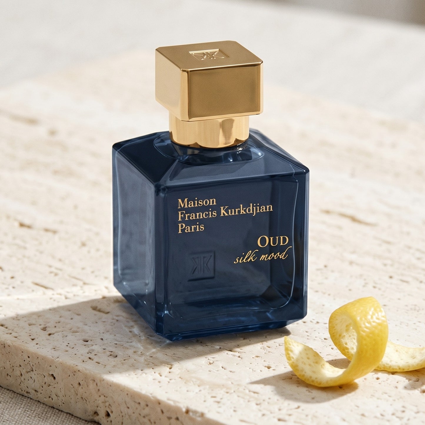 Maison Francis Kurkdjian (MFK) Oud Silk Mood EDP on pale travertine with a lemon peel curled beside the bottle