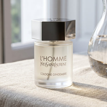 Yves Saint Laurent Lhomme Gingembre Cologne on raw linen, sun-bleached with a glass carafe of water catching light