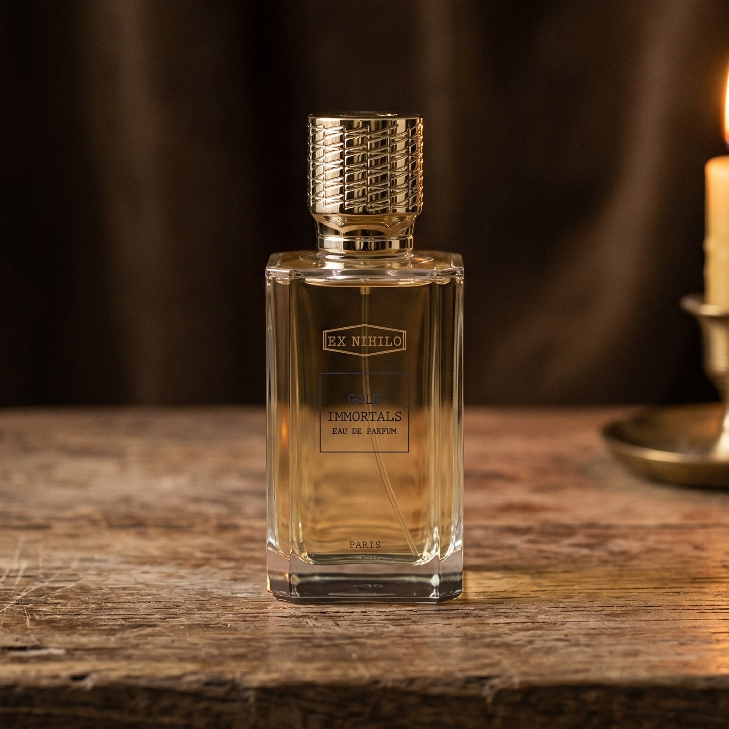 Ex Nihilo Gold Immortals EDP on aged teak with a candle burning gently to frame-right