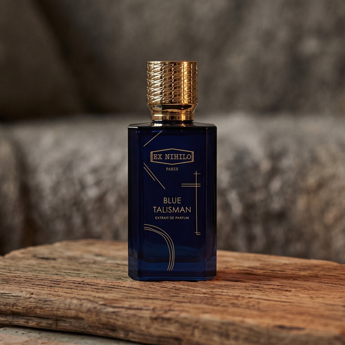 Ex Nihilo Gold Immortals Extrait EDP on aged teak with a candle burning gently to frame-right