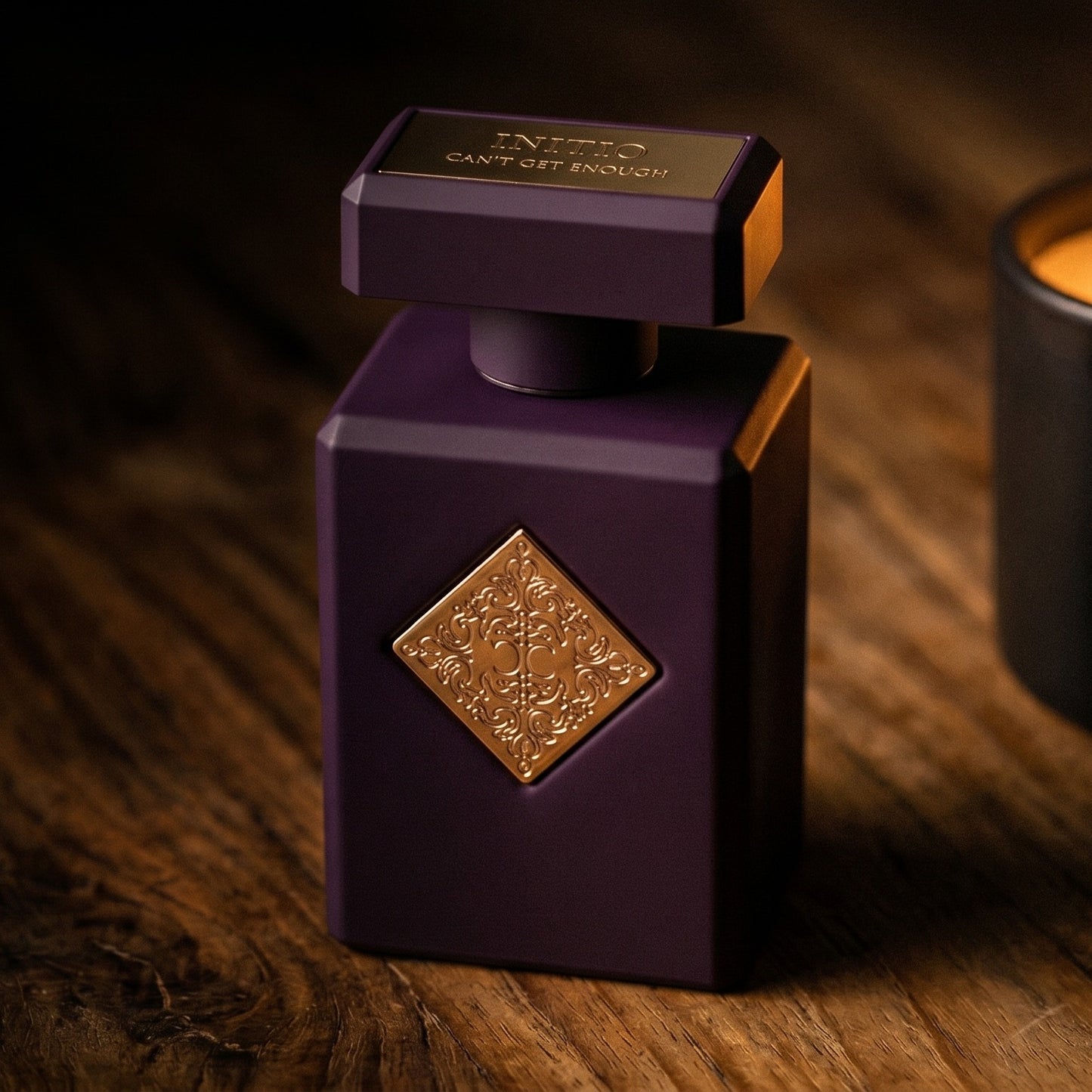 Initio Can't Get Enough EDP on aged teak with a candle burning gently to frame-right