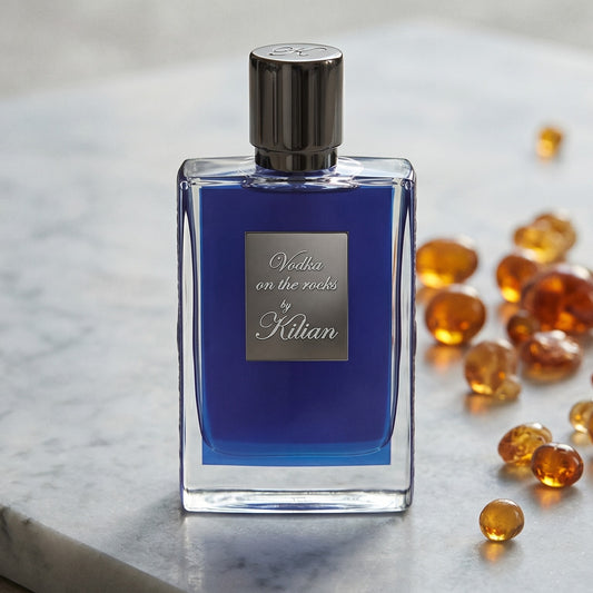 Kilian Vodka On The Rocks EDP on pale grey marble with amber resin beads scattered to one side