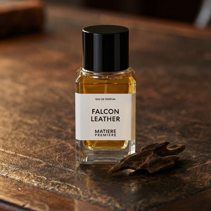 Matiere Premiere Falcon Leather EDP on aged leather-topped desk with a single agarwood chip beside the bottle