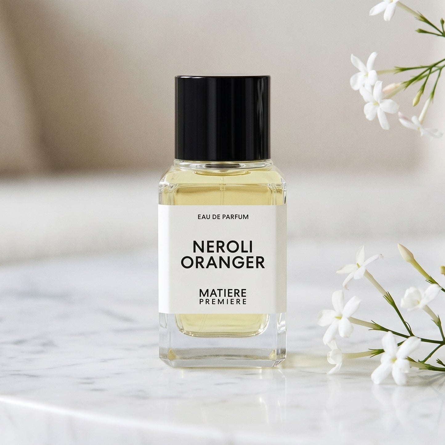 Matiere Premiere Neroli Oranger EDP on white carrara marble with jasmine sprigs placed to frame-right