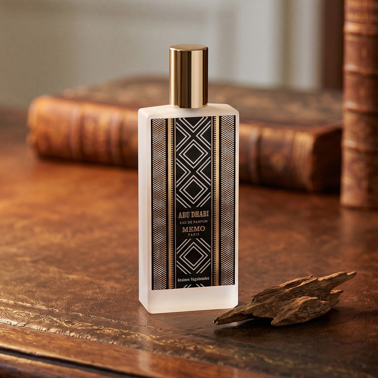 Memo Paris Abu Dhabi EDP on aged leather-topped desk with a single agarwood chip beside the bottle